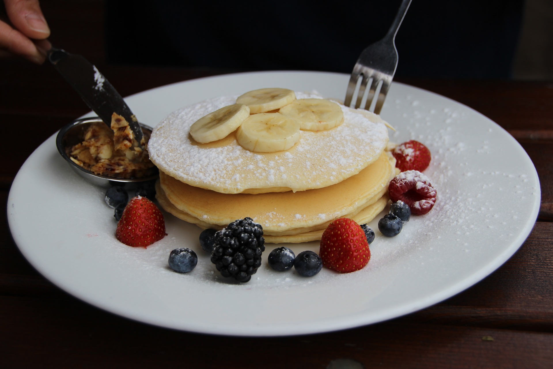 PANQUECAS NO PRATO COM BANANAS E FRUTAS VERMELHAS