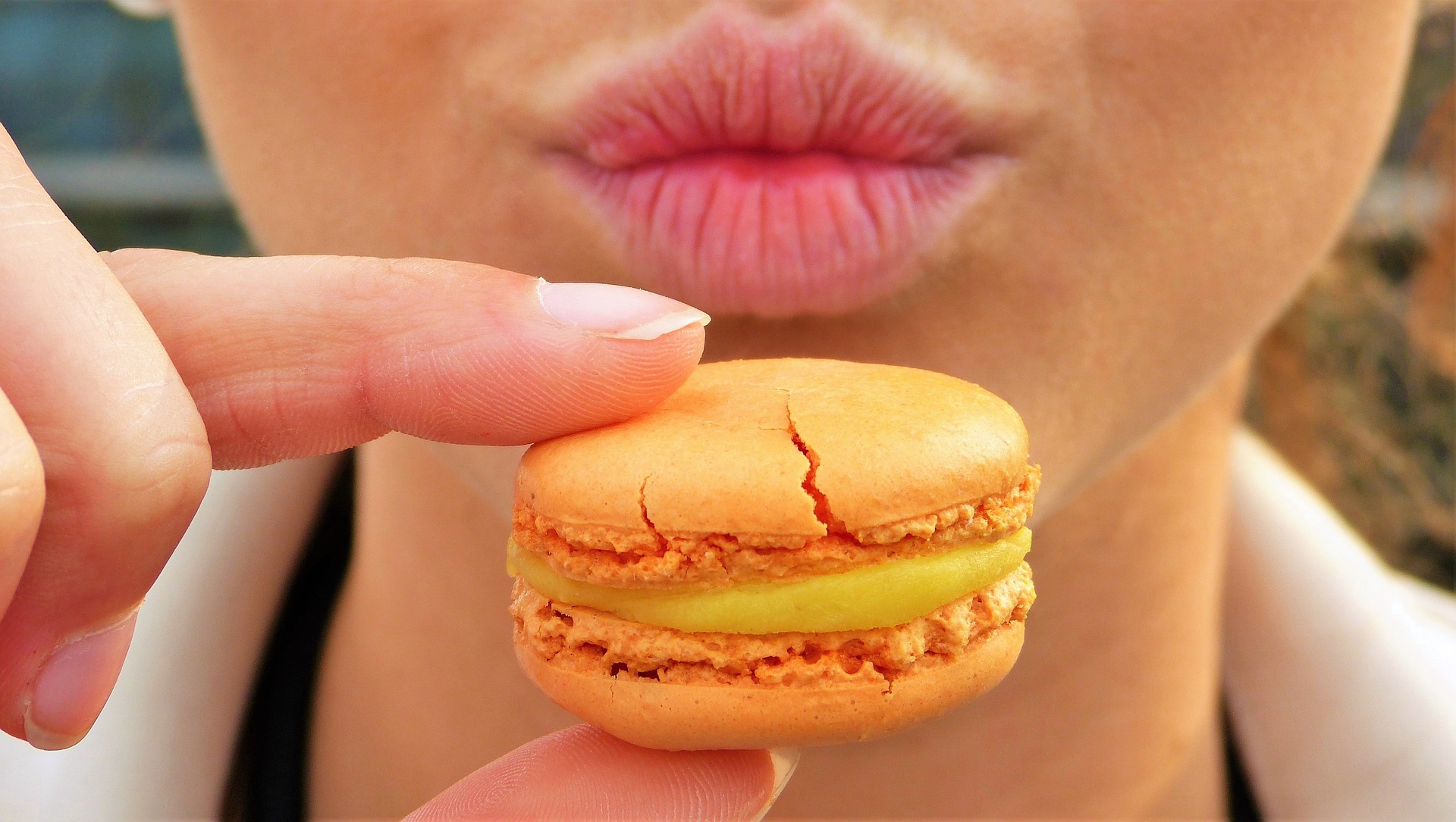 MÃO SEGURANDO UM MACARON PERTO DA BOCA